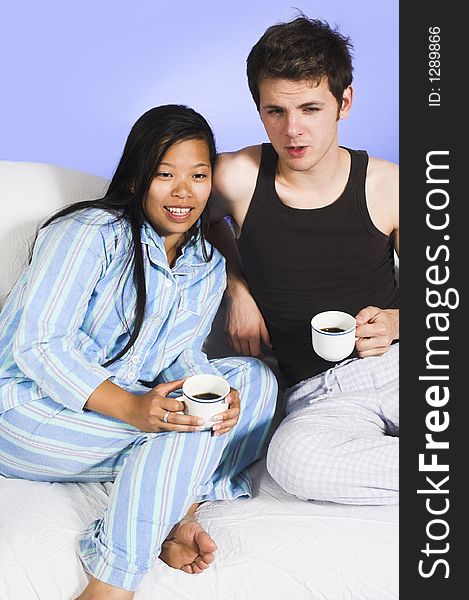Couple drinking coffee on couch over blue background