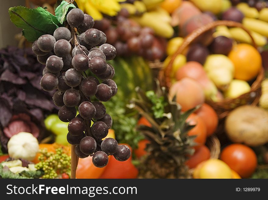 Grapes in front of a huge pile of other fruits and vegetables. Grapes in front of a huge pile of other fruits and vegetables