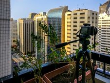 Shooting A Time Lapse Of The Sunset In A Balcony In The City - Camera And Tripod Stock Photography