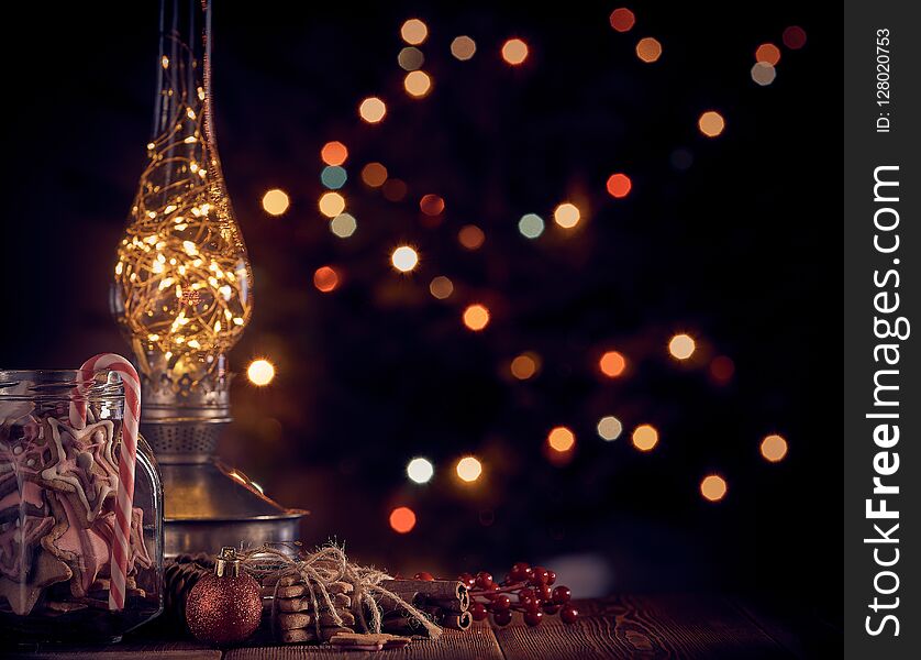 Christmas decor and gingerbread cookies lying on a wooden table on a dark background with light of garland. Copy space for text. Christmas and New Year. Christmas decor and gingerbread cookies lying on a wooden table on a dark background with light of garland. Copy space for text. Christmas and New Year.