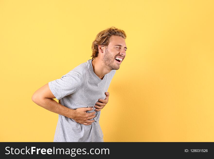 Handsome young man laughing on color background