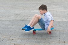Boy Riding On A Blue Skateboard On The Road In A City Park Royalty Free Stock Photography