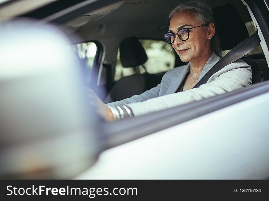 Mature businesswoman concentrating on road while driving a car. Senior female entrepreneur traveling to work in her car. Mature businesswoman concentrating on road while driving a car. Senior female entrepreneur traveling to work in her car.