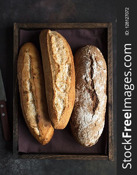 Various fresh homemade bread in rustic wooden box, top view, copy space. Sourdough mini baguette wheat and rye bread. Various fresh homemade bread in rustic wooden box, top view, copy space. Sourdough mini baguette wheat and rye bread.