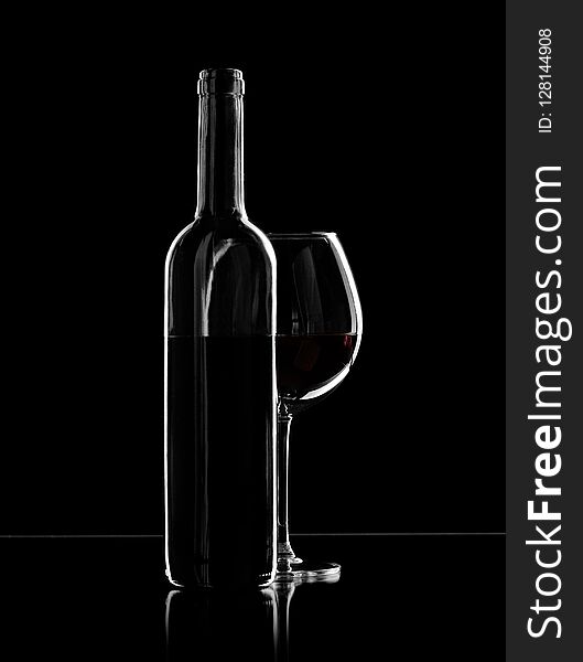 Bottle and wine glass with red wine, photo on black background. Bottle and wine glass with red wine, photo on black background