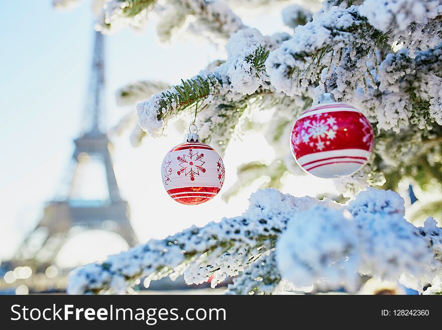Christmas tree covered with snow and decorated with red toys near the Eiffel tower in Paris, France. Christmas tree covered with snow and decorated with red toys near the Eiffel tower in Paris, France