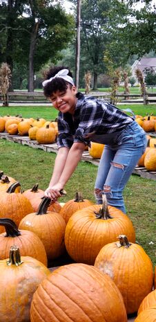 Teen Girl Picking Up A Pumpkin In A Pumpkin Patch Royalty Free Stock Image