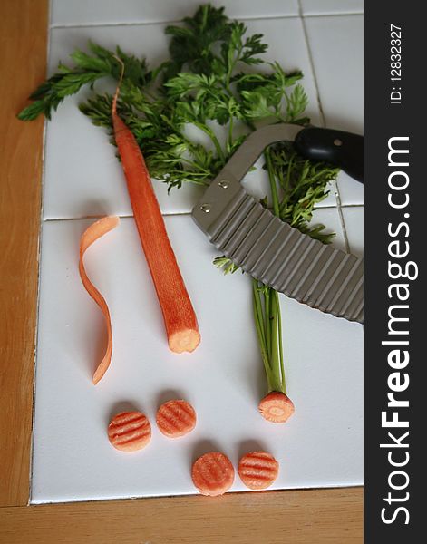Carrot with green top and crinkle cutter with slices of carrot. Carrot with green top and crinkle cutter with slices of carrot