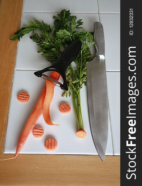 Carrot with green top and peeler with slices of carrot. Carrot with green top and peeler with slices of carrot
