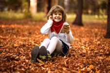 Happy Little Girl Sits On Yellow Leaves And Listens To Music In Autumn Royalty Free Stock Photos