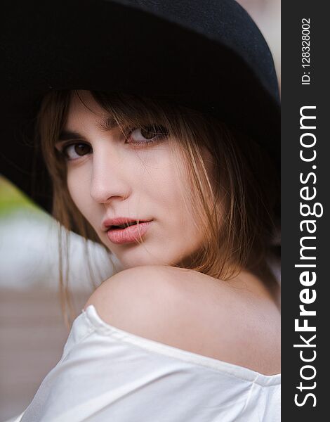 Closeup portrait of attractive young woman wearing black hat posing at the city