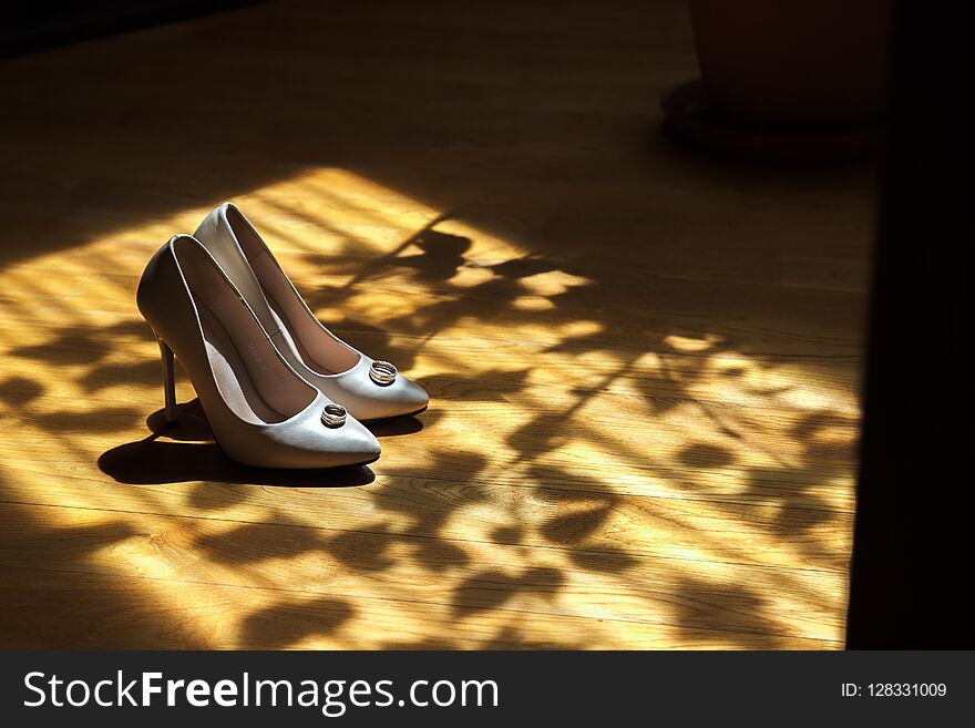White beautiful wedding shoes in dark shade in sunlight