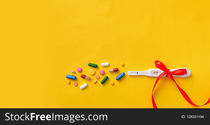 Pregnancy test, pills and vitamins on a yellow background. Health of the child and mother.