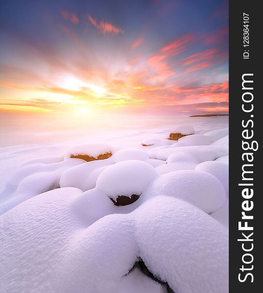 Winter sunset with snow-covered rocks. Composition of nature