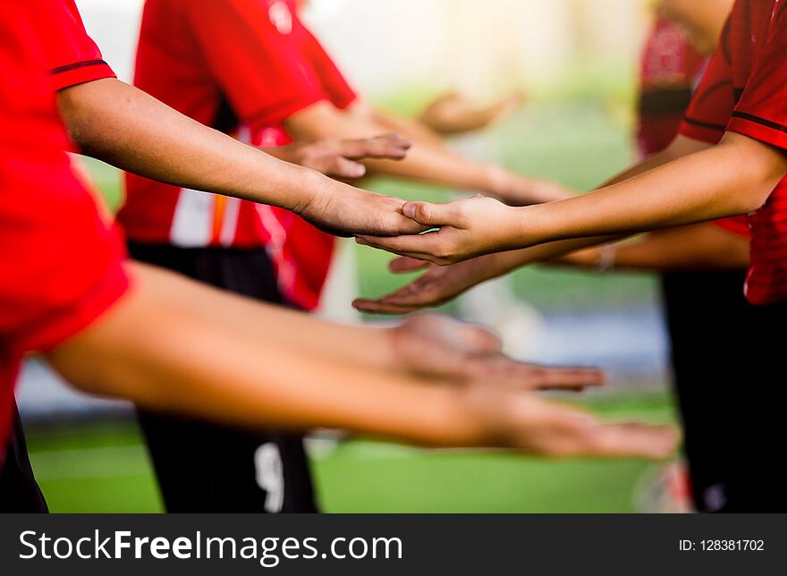 Young boy soccer players tap hands together for football training.