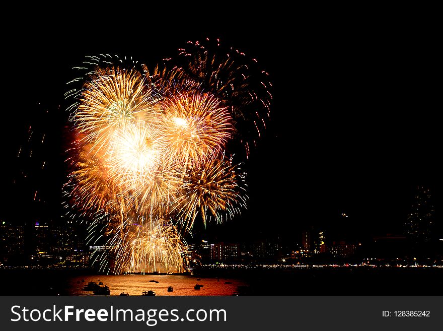 Many flashing fireworks with night cityscape background celebrate New Year.