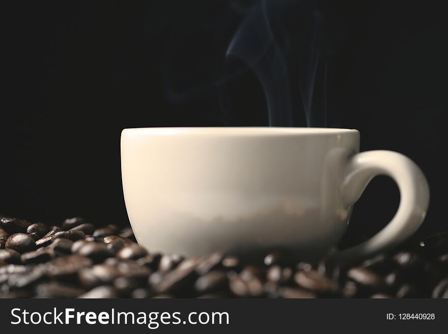 Coffee beans and coffee cup with smoke, closeup