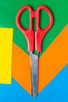 Scissors Lie On Multicolor Paper. Green, Orange, Yellow, Blue Royalty Free Stock Photos