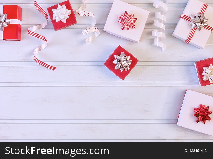 Red and white gift boxes with beautiful bows, decorative ribbons. Christmas composition with place for text, copy space. Festive photo on a pale blue background.