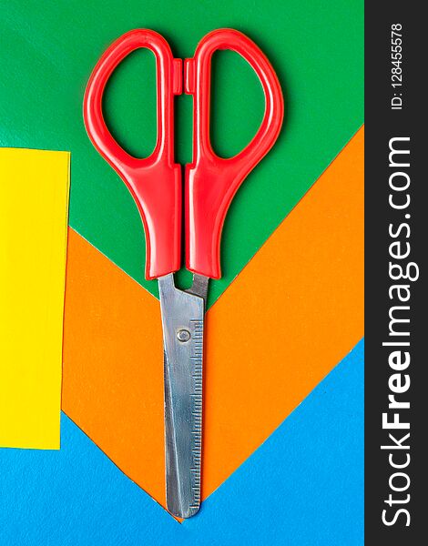 Scissors Lie On Multicolor Paper. Green, Orange, Yellow, Blue