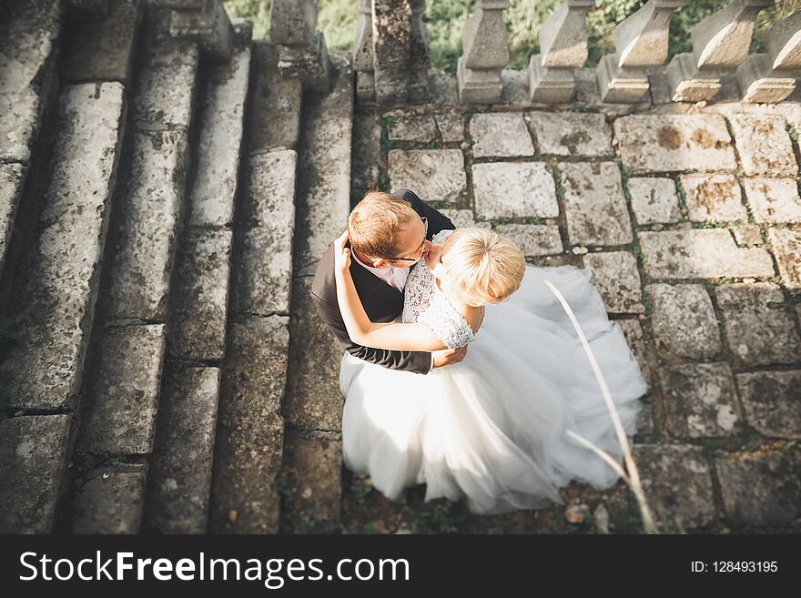 Beautiful fairytale newlywed couple hugging near old medieval castle.