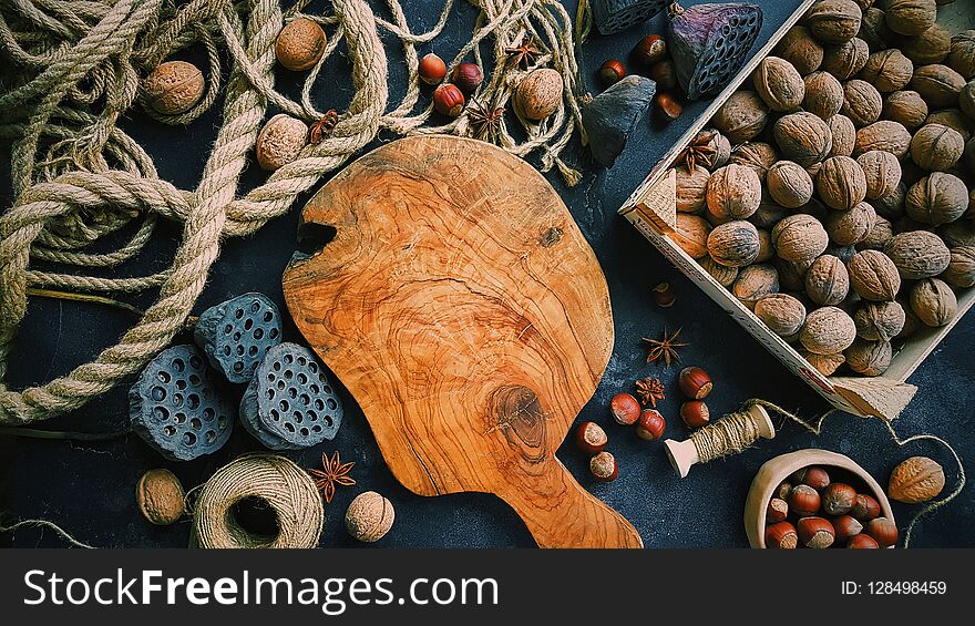 Wooden Board In The Center, Autumn Still Life On Dark Background, Nuts, Ropes And Flowers, Rustic Life