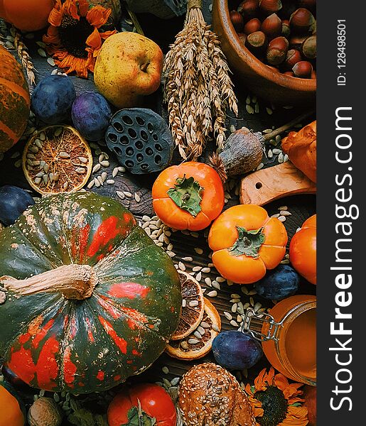 Autumn still life, Harvest, Pumpkins, persimmon, plums, nuts, wheat, homemade bread on dark wooden background, Rustic life