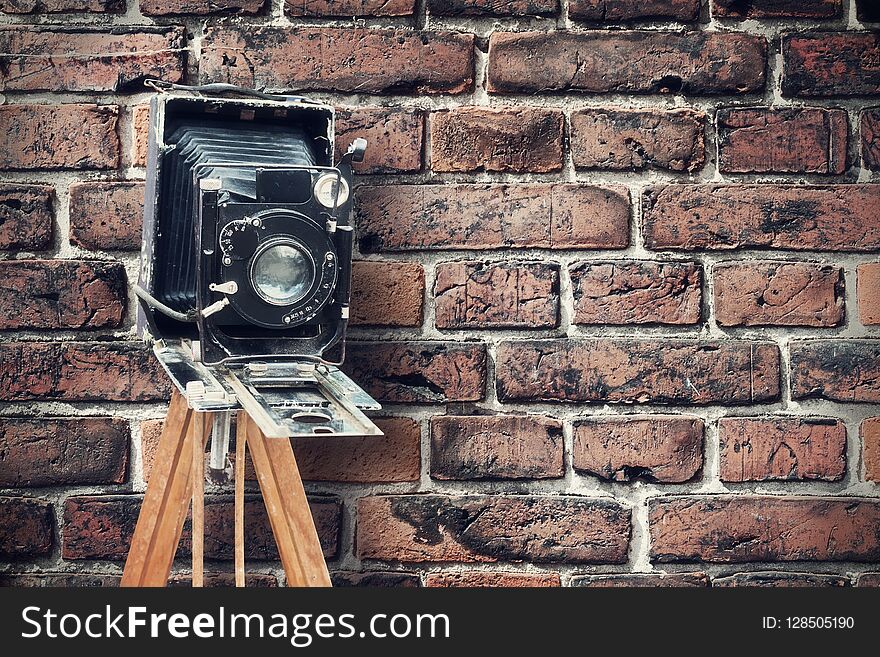 Old vintage camera against a brick wall. Concept photo studio.