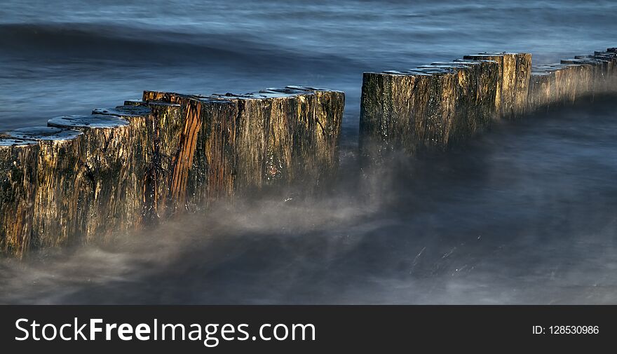 Wooden groynes in the blue sea, smooth water by long exposure, n