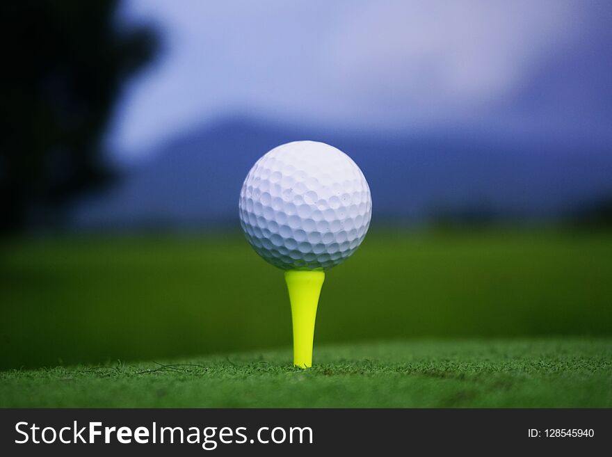 Golf Ball On Tee In Beautiful Golf Course At Sunset Background.