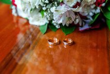 Wedding Rings Lie On Wooden Surface Against Background Of Bouquet Of Flowers Royalty Free Stock Photos
