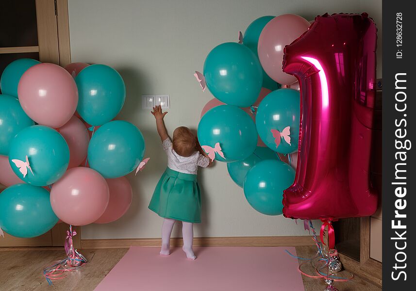 small child reaching for a light switch, near balloons, first birthday. curiosity.
