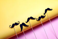 Many Black Paper Mutaches On Pink And Yellow Background. Stock Photo Many Black Paper Mutaches On Pink And Yellow Background. Stock Photo