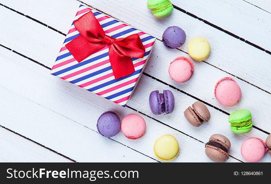 Gift box and french macaron on white wooden background. Gift box and french macaron on white wooden background