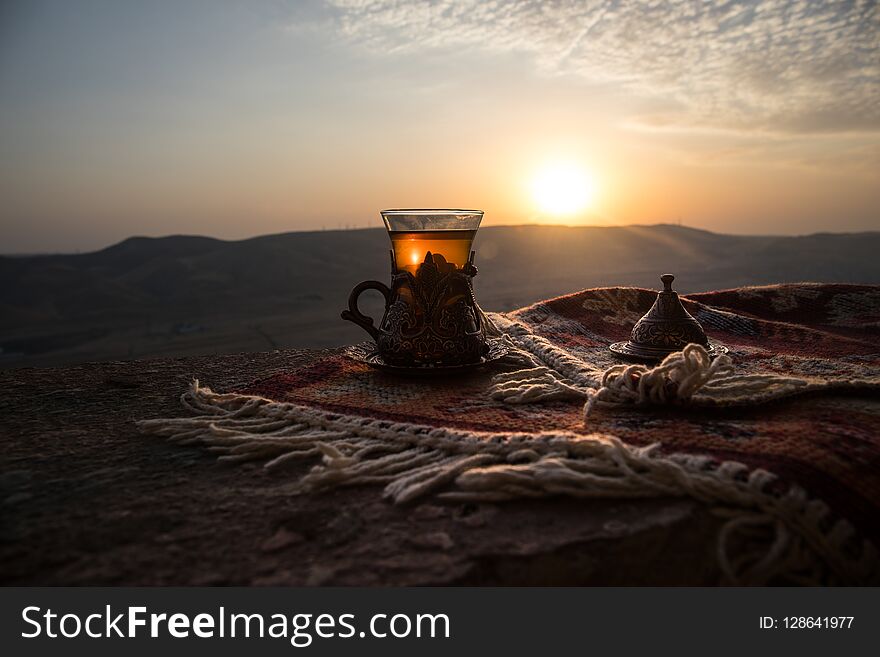 Arabian tea in glass on a eastern carpet. Eastern tea concept. Armudu traditional cup. Sunset background. Selective focus