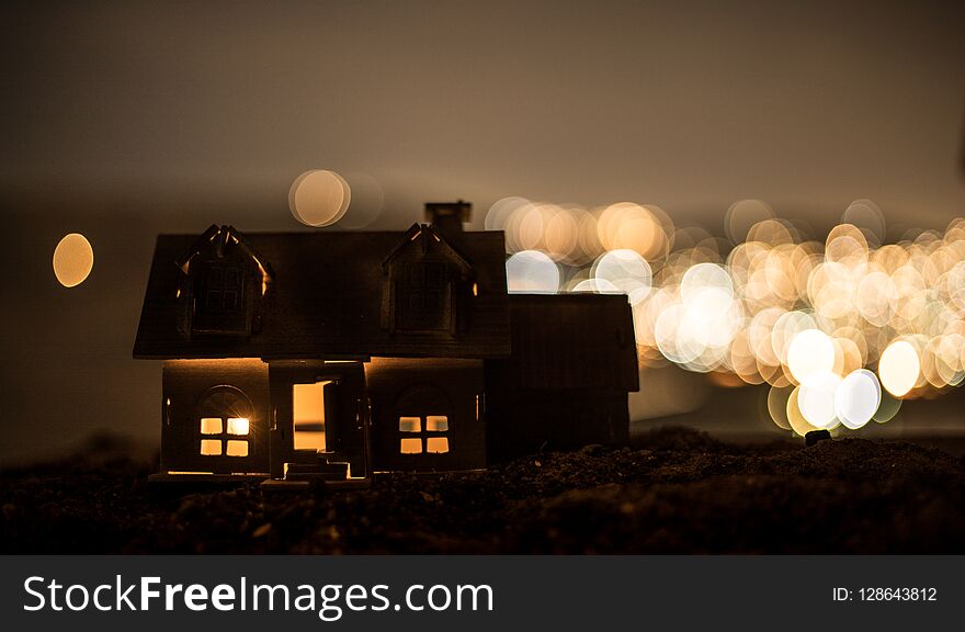 Little decorative house, beautiful festive still life, cute small house at night, Night city real bokeh background, happy winter holidays. Selective focus