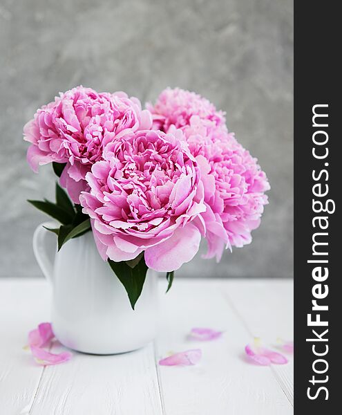 Vase with pink peony flowers on a white wooden table