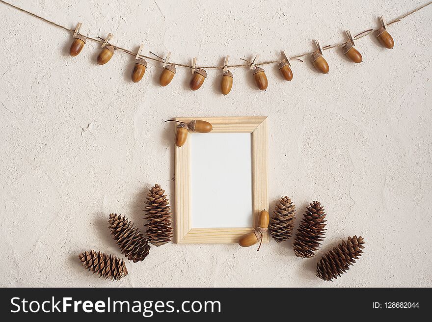 Autumn composition with wooden frame. Acorn with clothespins on clothes line rope. Wooden pegs. Flat lay, top view, copy space.