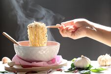 Woman Hand Holding Fork Of Instant Noodles In Cup With Smoke Rising And Garlic On Dark Background, Sodium Diet High Risk Kidney F Royalty Free Stock Photography