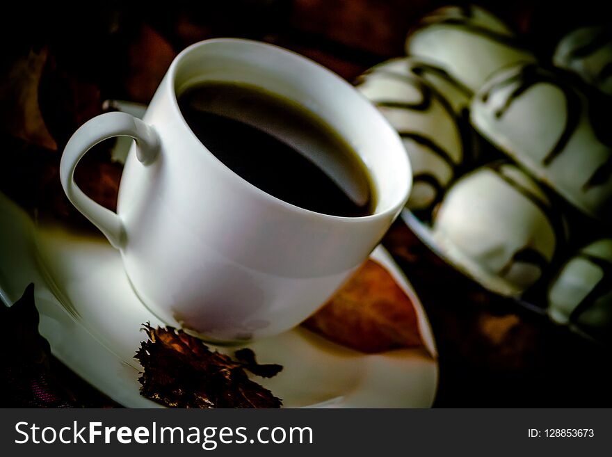 White Cup And Saucer With Tea Or Coffee Is On The Table, Autumn Orange Leaves