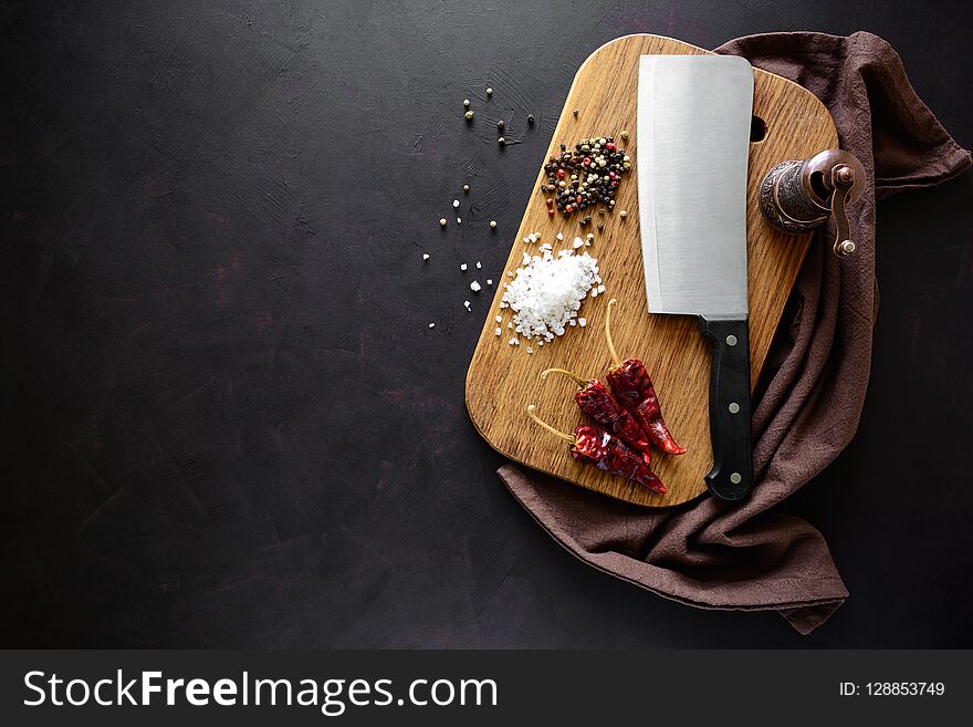 Rectangular catting board with ingredients for cooking and knife on dark wooden background. Top view.
