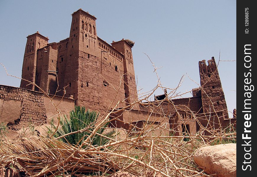 Moroc-The Kasbah of Aït Benhaddou, is a 'fortified city', or ksar, along the former caravan route between the Sahara and Marrakech in present-day Morocco. is a term describing a Berber village consisting of generally attached houses, often having collective granaries and other structures (mosque, bath, oven, shops) widespread among the oasis populations of the Maghreb (northern Africa.) Ksars are sometimes situated in mountain locations to make defense easier; they often are entirely within a single, continuous wall. The building material of the entire structure is normally adobe, or cut stone and adobe. The idea of the ksar as a granary is a confused notion of two things, the granary itself, found within a ksar, and the ksar, which is a village, normally with granaries within it. Ksars form one the main manifestations of Berber architecture.