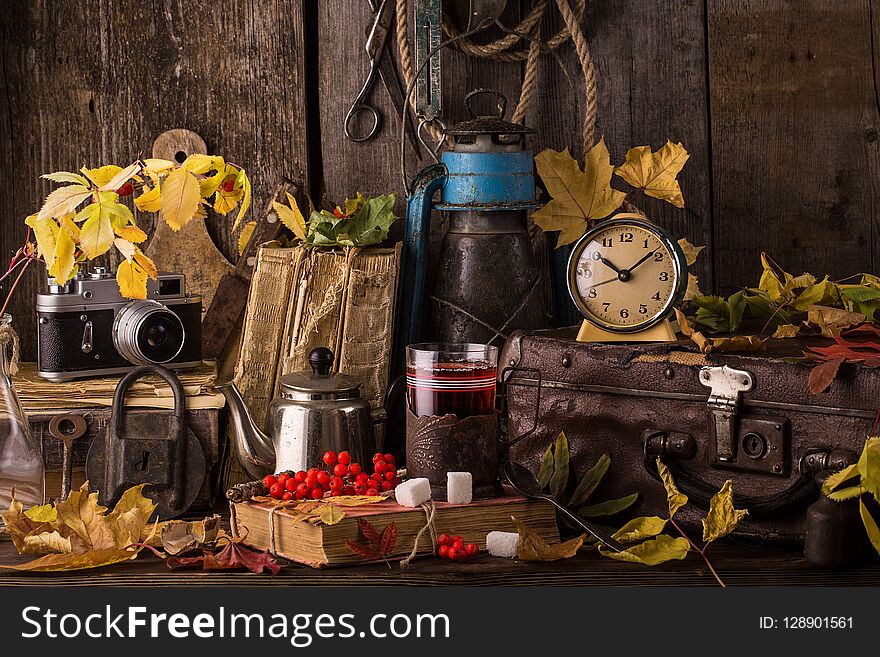 Romantic autumn still life with books, vintage suitcase, old clock and leaves. Vintage still life