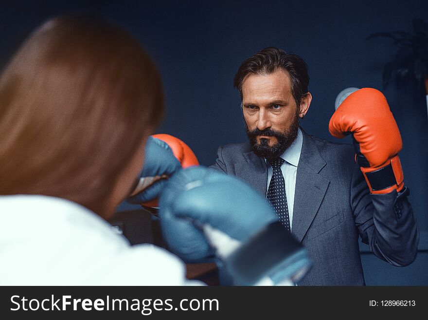 Business colleagues in office clothes and boxing gloves. Compete in business. Fight of genders concept. Business colleagues in office clothes and boxing gloves. Compete in business. Fight of genders concept.