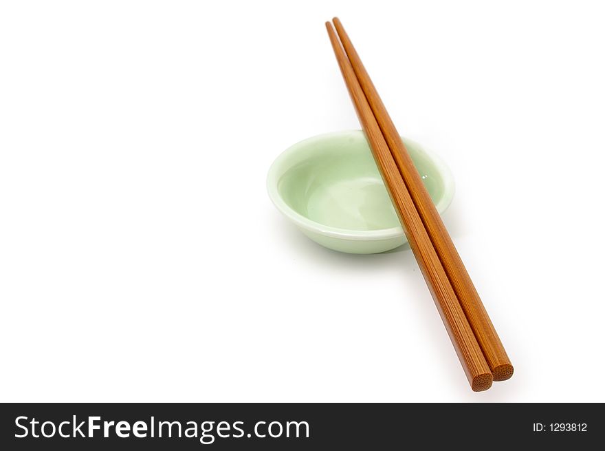 A pair of wooden chopsticks rest on a ceramic bowl. A pair of wooden chopsticks rest on a ceramic bowl.