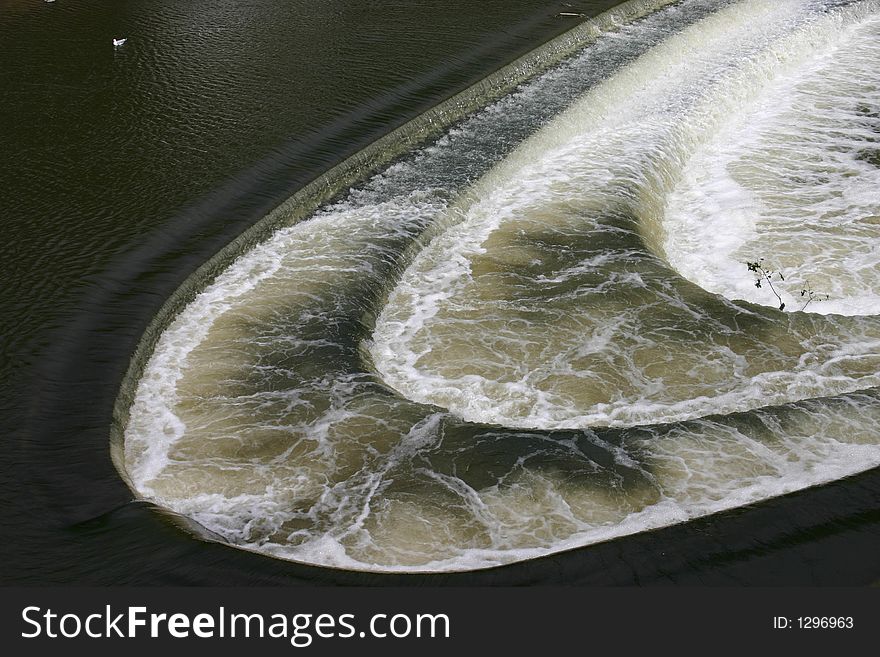 Curved Weir in bath with water flowing fast down river. Curved Weir in bath with water flowing fast down river