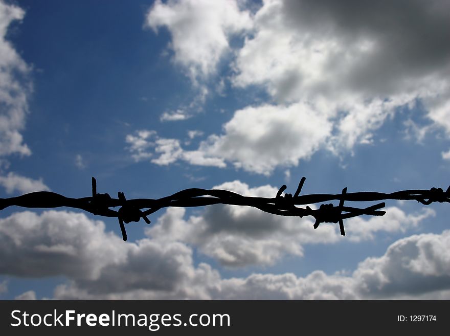 Barbed wire on a sunny day with blue sky, silhouette