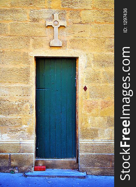 Old door on the side of a chapel in adorned with a stone cross in Aix-en-Provance, France. Old door on the side of a chapel in adorned with a stone cross in Aix-en-Provance, France