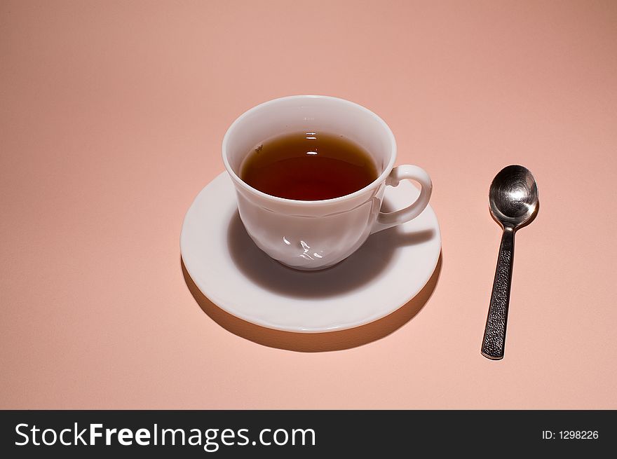 White cup of tea on plate with spoon beside.