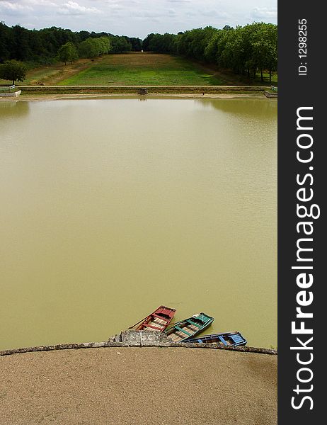 Three cute rowboats in mismatched colours on an artificial lake in the Loire valley. Three cute rowboats in mismatched colours on an artificial lake in the Loire valley